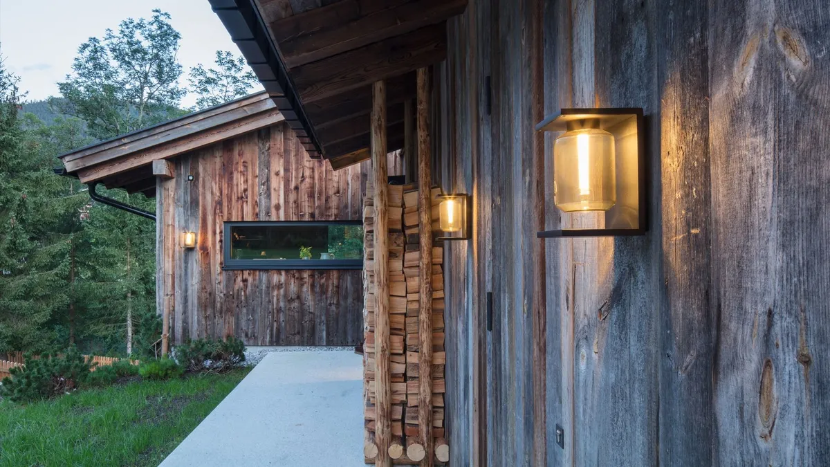 Ancienne grange en bois éclairée par une applique extérieure à la nuit tombée