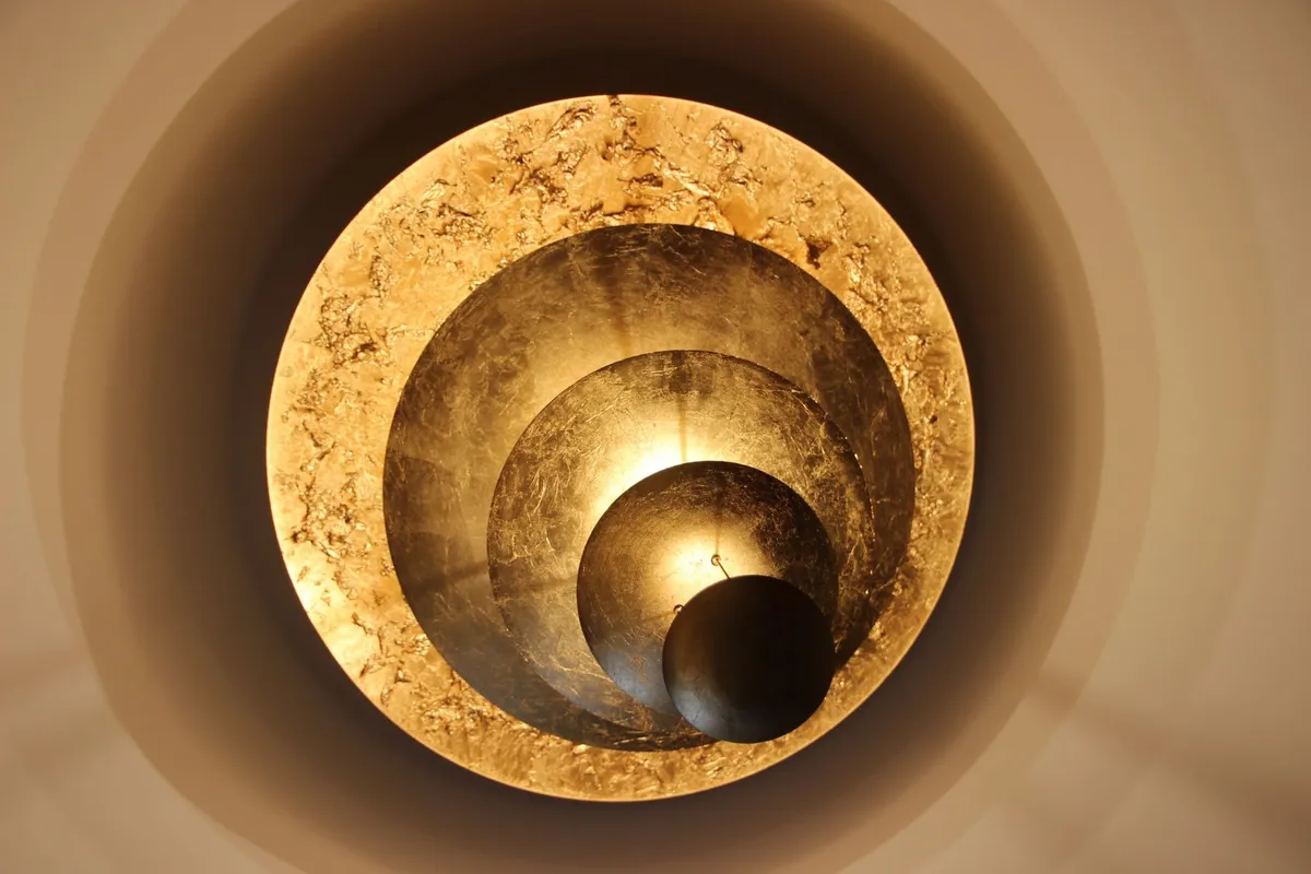 Détail d'un luminaire en feuille d'or diffusant une lumière chaude